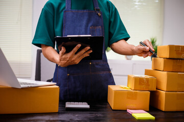 close-up of a man's hands working meticulously with a cardboard box on wooden desk, representing an...