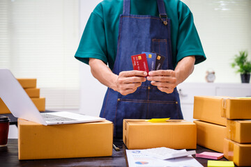 close-up of a man's hands working meticulously with a cardboard box on wooden desk, representing an...