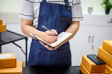 close-up of a man's hands working meticulously with a cardboard box on wooden desk, representing an...