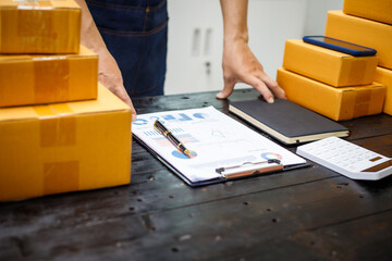 close-up of a man's hands working meticulously with a cardboard box on wooden desk, representing an online seller effort to pack products, successful business operations and customer satisfaction.