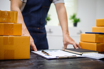 close-up of a man's hands working meticulously with a cardboard box on wooden desk, representing an online seller effort to pack products, successful business operations and customer satisfaction.