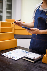 close-up of a man's hands working meticulously with a cardboard box on wooden desk, representing an...