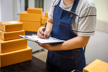 close-up of a man's hands working meticulously with a cardboard box on wooden desk, representing an...