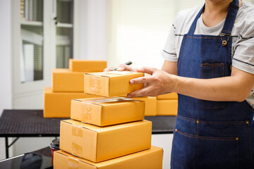 close-up of a man's hands working meticulously with a cardboard box on wooden desk, representing an online seller effort to pack products, successful business operations and customer satisfaction.