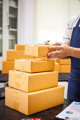 Fototapeta premium close-up of a man's hands working meticulously with a cardboard box on wooden desk, representing an online seller effort to pack products, successful business operations and customer satisfaction.