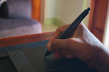 Hand holding stylus pen to draw on graphics tablet device 1