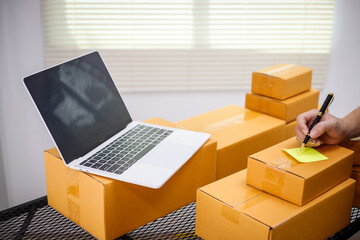 close-up of a man's hands working meticulously with a cardboard box on wooden desk, representing an online seller effort to pack products, successful business operations and customer satisfaction.