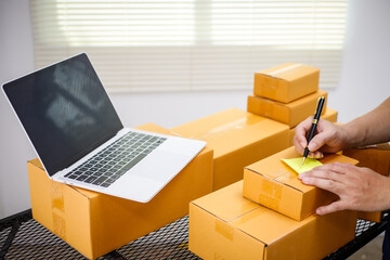 close-up of a man's hands working meticulously with a cardboard box on wooden desk, representing an...