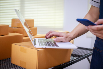close-up of a man's hands working meticulously with a cardboard box on wooden desk, representing an...