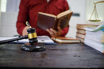 close-up of a lawyer’s hands working at a desk, reviewing legal documents and contracts, with a wooden gavel nearby, symbolizing law, legislation, and the potential complexities of bribery cases.