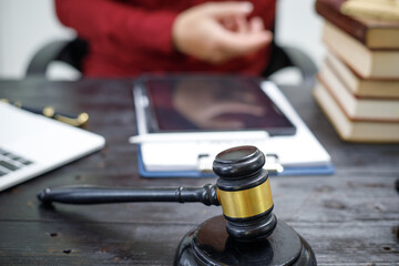 close-up of a lawyer’s hands working at a desk, reviewing legal documents and contracts, with a wooden gavel nearby, symbolizing law, legislation, and the potential complexities of bribery cases.