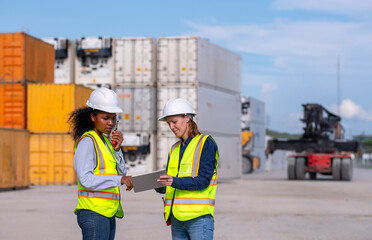 Engineers wearing safety gear, including hard hats examining survey a large blueprint tablet standing industrial facility gas or oil refinery engaged in a job requires high safety standards concept