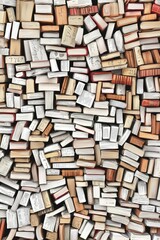 Fototapeta premium Aerial view of a large collection of closed books stacked haphazardly in various orientations.