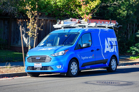 Blue ADT service van is parked on a residential street. The vehicle is equipped with roof-mounted ladders - California, USA - September 30, 2024