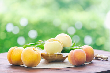Fresh three kinds of peaches on blurred greenery background, Three colored peaches in basket on wooden table in garden.