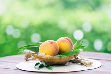 Fresh white peach in Bamboo basket on wooden table in garden, Sweet Pink Peach fruits in blur background.