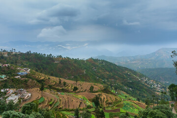 Step agriculture, or terrace agriculture. Steep hills or mountainsides are cut to form level areas for planting of crops. Foggy, misty Himalayan mountains background, Garhwal, Uttarakhand, India.