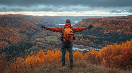 A hiker enjoys a scenic autumn view with arms outstretched over a colorful landscape.