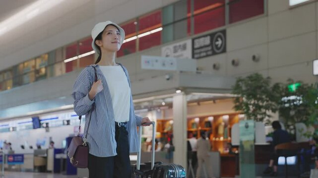 スーツケースを持って空港を歩く旅行中の日本人の女性	
