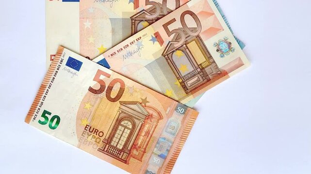 4K footage video of Euro banknotes dropped, thrown, and scattered on a white background. Counting Euro money banknotes from the nominal of 50 Euro to 20 and 10 Euro. Isolated white background.
