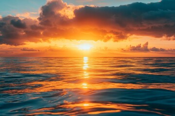 Fototapeta premium Orange sunset reflected in calm ocean water.