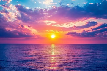 Obraz premium A vibrant sunset over a calm ocean with pink and orange clouds reflecting in the water.