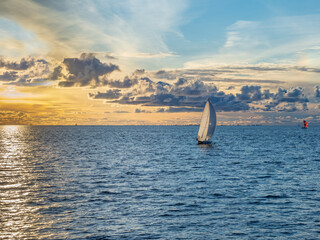 Small sailing yacht in the sea at sunset