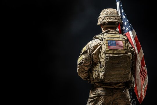 A soldier in camouflage uniform holding a US flag on a black background.