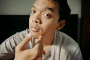A man examining his facial hair while touching his chin, appearing thoughtful and focused