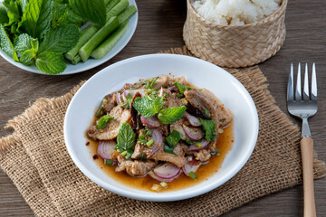 Grilled pork salad on the wooden table. Thai food. Isaan food.