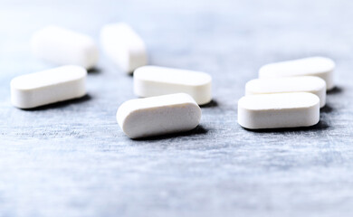 Amino acids tablets. Nutrition for bodybuilding. Fitness supplements on bright wooden background. Soft focus. Copy space.	