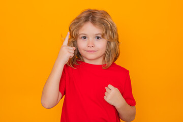 Child have idea on yellow isolated background. Child pointing up finger, on yellow background. Shocked kid pointing up, thinking.