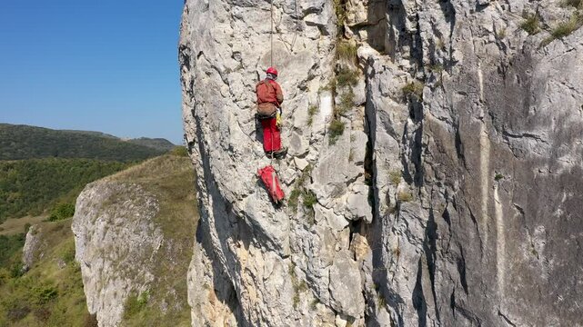 Aerial view of mountain rescuer doing rescue operations hanging on a rope