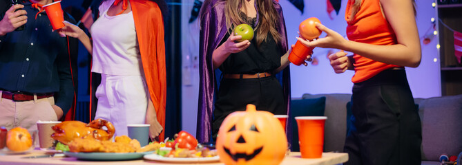 Halloween party with friends in costumes, enjoying drinks, food, and festive decorations. Perfect for autumn gatherings
