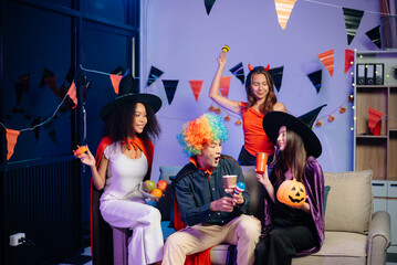 Halloween party with friends in costumes, enjoying drinks, food, and festive decorations. Perfect...