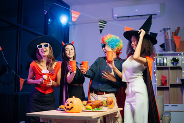 Halloween party with friends in costumes, enjoying drinks, food, and festive decorations. Perfect...