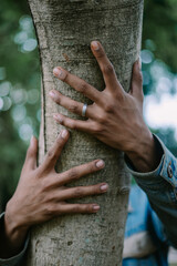 Close-up of a hand holding a tree trunk, symbolizing a connection with nature.