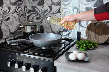 A man cooks an omelet in a non-stick frying pan on a gas stove in his home kitchen.