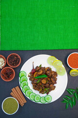 prawn fry and prawn pepper fry along with onion slice, lemon slice, cucumber slice, Star anise, cinnamon, chicken gravy and spices on white plate with green cloth