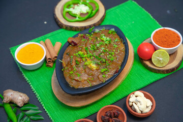 chicken gravy, mutton gravy along with onion, ginger, cashews, lemon, Star anise, cinnamon, pepper, clove, chutney, tomato and spices on black bowl and green towel