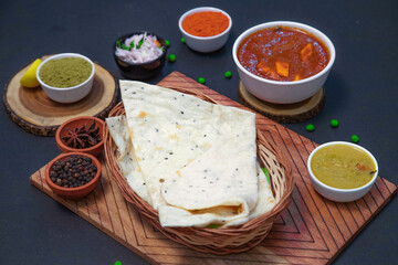 Homemade Naan, butter naan, garlic naan along with onion or creamy onion raita, lemon, Star anise, clove, chicken gravy and spices on wooden bamboo plate