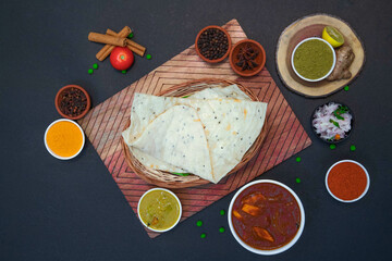 Homemade Naan, butter naan, garlic naan along with onion or creamy onion raita, lemon, Star anise, clove, chicken gravy and spices on wooden bamboo plate