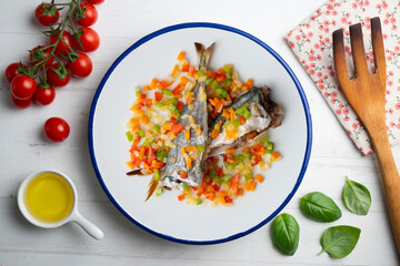 Baked horse mackerel with chopped vegetables. Top view table with  decorations.