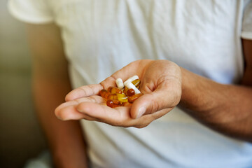 Close-up of a person's hand holding a variety of pills and capsules