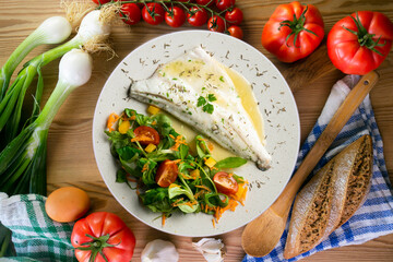 Baked sea bass with lemon sauce. Top view table with decorations.