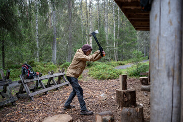man chopping firewood with an axe for making a fire in the forest