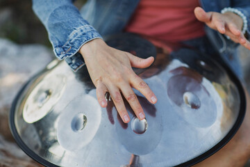 Woman's hands playing handpan drum close-up