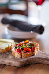 A bruschetta board sitting a wood table vertical