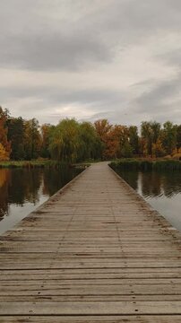 A wooden bridge over a still lake in a park Stromovka in Prague
