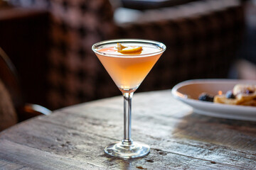 Gold colored cocktail in a martini glass with garnish